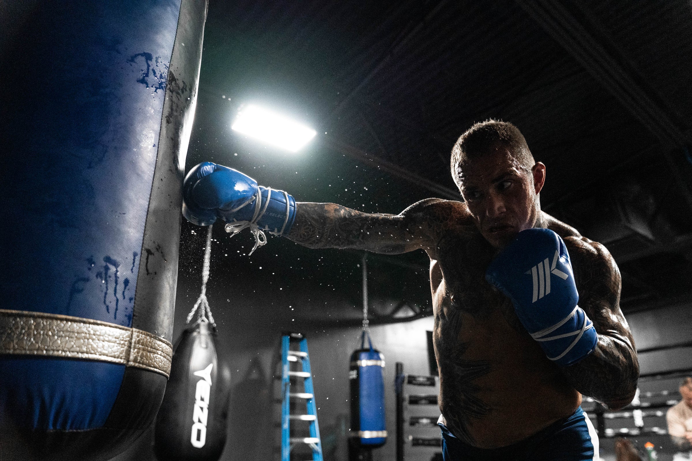Professional fighter Jake Bostwick punching the heavy bag with MK1's Select Lace Up Boxing Gloves during the closeout of a training camp for an upcoming fight.  