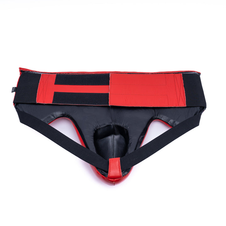 Red groin guard closure featuring a velcro strap for a secure fit during sparring.